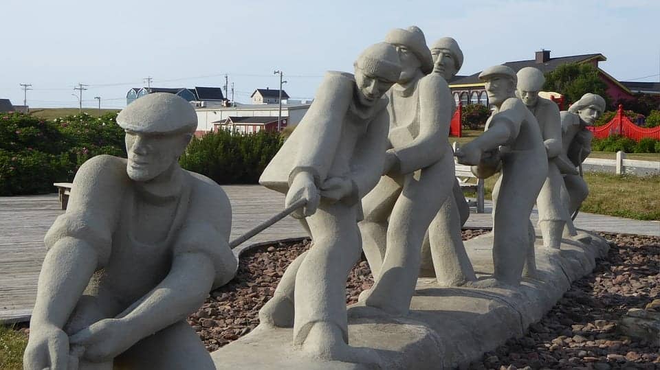 concrete sculpture of humans pullin on a rope together