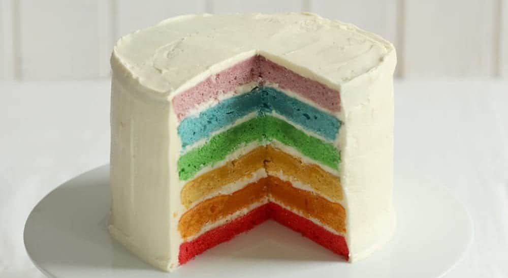 rainbow cake with white icing on white plate