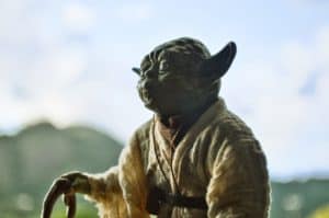 yoda standing with a cane in front of blurred mountain background