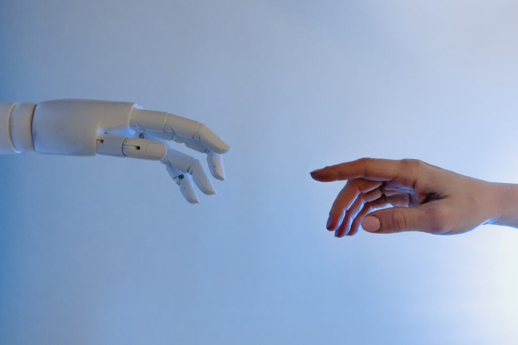A robot hand reading out to a human hand, reminiscent of Michelangelo's The Creation of Adam