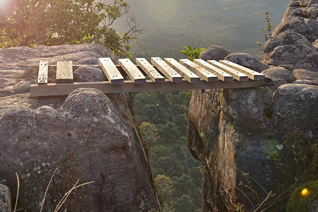 wooden bridge across a gap between mountain rocks
